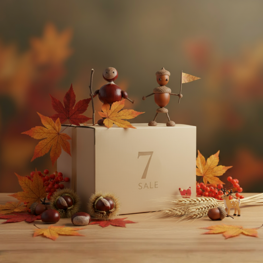 Herbstliche Szene mit Kastanienfiguren, bunten Herbstblättern, Naturmaterialien und einer  7sale Geschenkbox auf einem Holztisch.